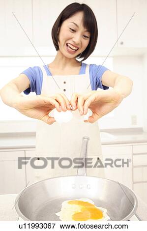 Woman making a fried egg View Large Photo Image Stock Photo - Woman making a fried egg. Fotosearch