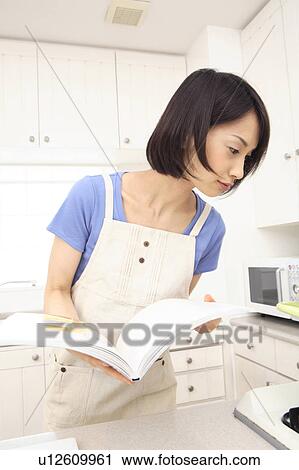 Stock Image - Woman reading cooking book. Fotosearch