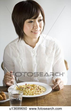 Stock Image - Young woman eating spaghetti. Fotosearch