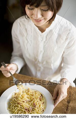 Stock Image - Young woman eating spaghetti. Fotosearch