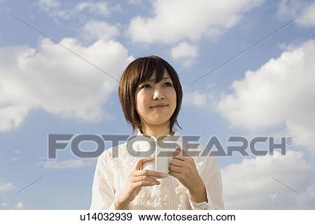 Stock Photo - Young woman holding cup. Fotosearch