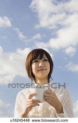 Stock Photo - Young woman holding cup. Fotosearch