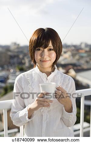 Young woman holding cup View Large Photo Image Stock Photo - Young woman holding cup. Fotosearch