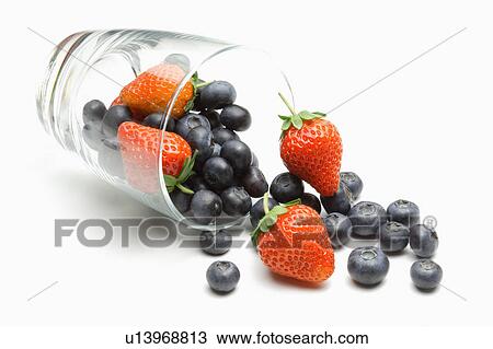 Stock Image - Glass of spilled blueberries and strawberries. Fotosearch