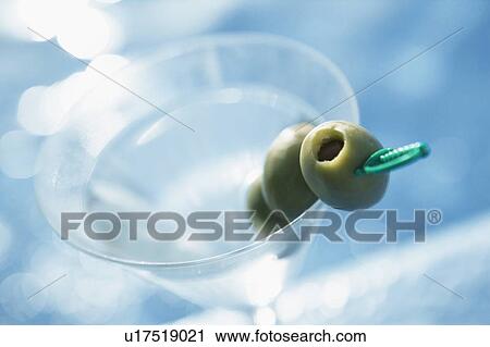Stock Image - Close-up of a glass of martini on the ledge of a swimming pool. Fotosearch