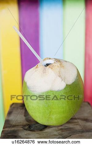 Stock Photograph - Close-up of a peeled coconut with a drinking straw. Fotosearch