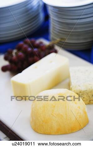 Close-up of slices of cheese with red grapes on a cutting board View Large Photo Image Stock Image - Close-up of slices of cheese with red grapes on a cutting board. Fotosearch