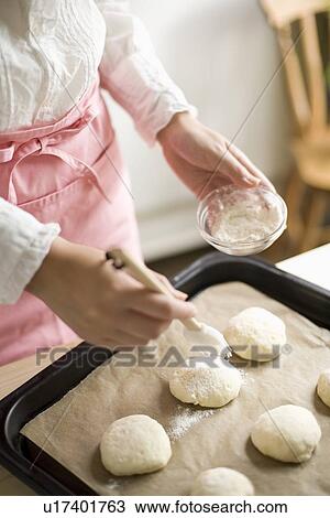Stock Image - Human hand of young woman baking bread. Fotosearch
