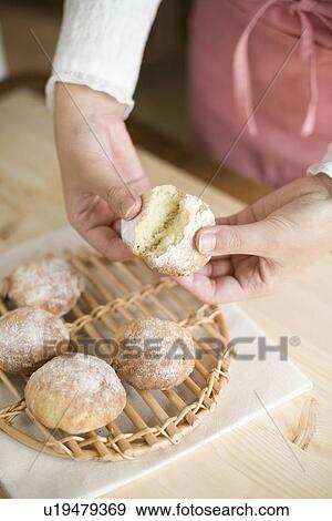 Stock Photo - Human hand of young woman breaking bread fresh from oven. Fotosearch