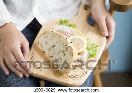 Stock Photo - Human hand of young woman holding sandwiches on board. Fotosearch