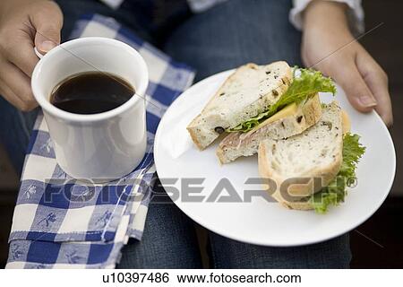 Stock Photograph - Human hand of young woman holding sandwiches. Fotosearch