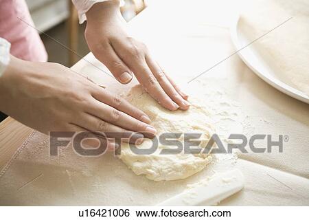 Stock Photograph - Human hand of young woman kneading dough. Fotosearch