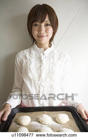 Stock Photo - Young woman holding baking tray. Fotosearch