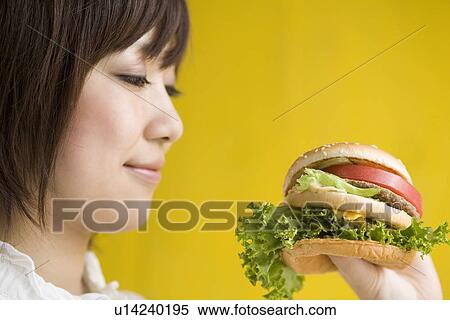 Stock Photography - Young woman holding hamburger. Fotosearch