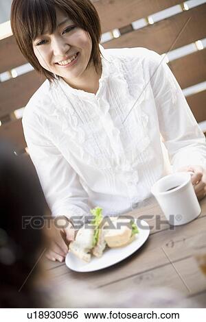 Young woman sitting at table View Large Photo Image Stock Photograph - Young woman sitting at table. Fotosearch