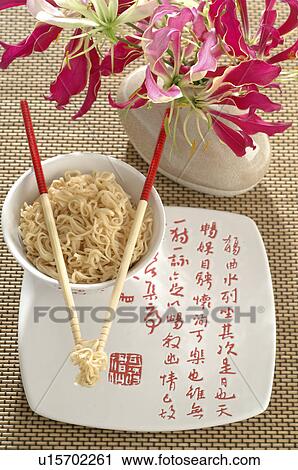 Stock Image - Asian noodles with chopsticks and a flower. Fotosearch