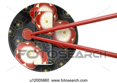 Stock Image - Asian plate with a flowery pattern and a pair of red chopsticks. Fotosearch
