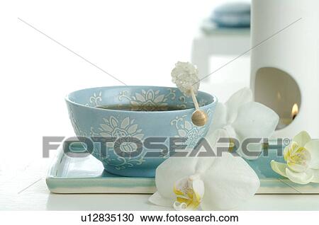 Stock Image - Teacup, candy and orchid blossoms. Fotosearch