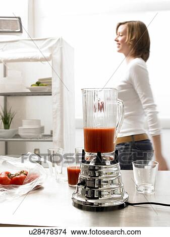 Blender with tomato juice and a woman in the background View Large Photo Image Picture - Blender with tomato juice and a woman in the background. Fotosearch