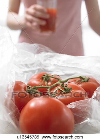 Stock Photography - Tomatoes and woman with a glass of tomato juice. Fotosearch