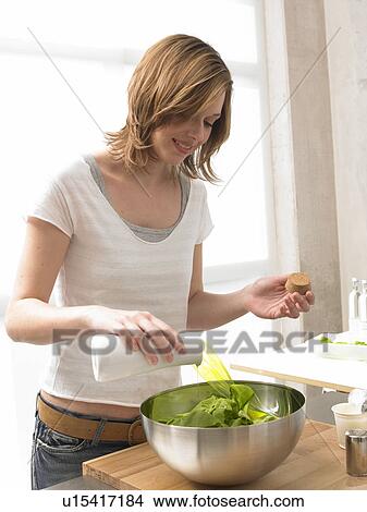 Picture - Woman is putting oil in the salad. Fotosearch