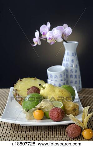 Fruits on a plate and a orchid blossoms in a Asian vase View Large Photo Image Stock Photo - Fruits on a plate and a orchid blossoms in a Asian vase. Fotosearch