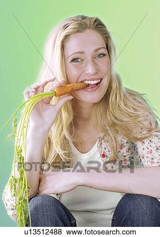 Stock Photo - Blonde woman eating carrot. Fotosearch
