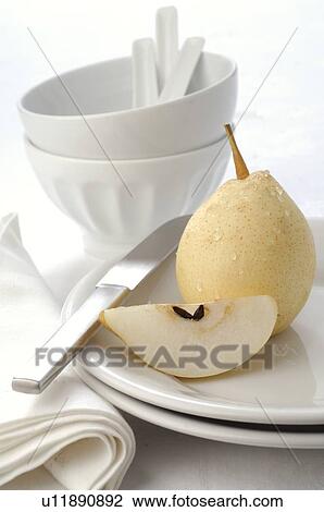 Stock Image - Pear on a plate with crockery. Fotosearch