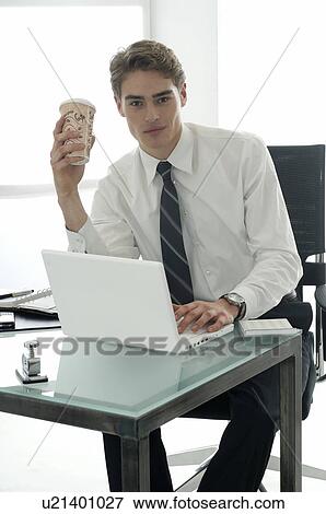 Stock Photo - Business man working with laptop is holding a paper coffee cup. Fotosearch