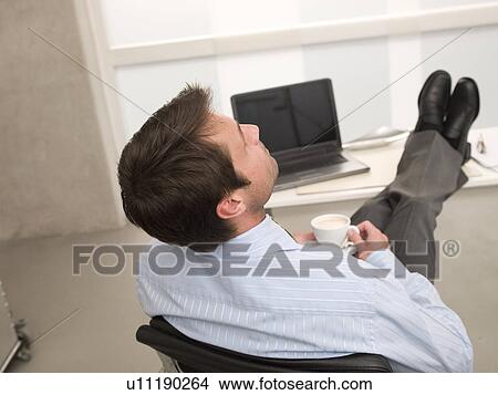 Picture - Man is drinking coffee at his desk. Fotosearch