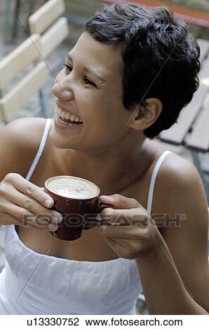 Stock Image - Young woman drinking cappuccino. Fotosearch