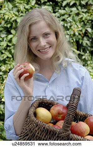 Stock Image - Woman with basket full of apples. Fotosearch