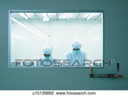 Stock Image - Two scientists wearing protective clothes behind security glass. Fotosearch