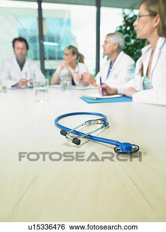 Business meeting of a group of doctors in a conference room around a table. Close up on stethoscope. View Large Photo Image Stock Photograph - Business meeting of a group of doctors in a conference room around a table. Close up on stethoscope.. Fotosearch