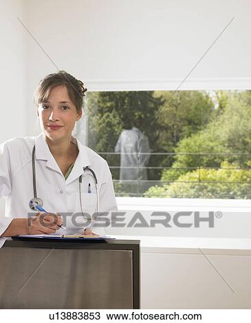 Female doctor filling up a file View Large Photo Image Stock Image - Female doctor filling up a file. Fotosearch