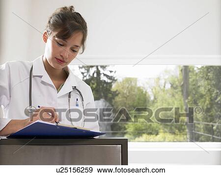 Female doctor filling up a file View Large Photo Image Stock Photo - Female doctor filling up a file. Fotosearch