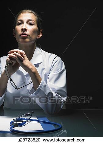 Portrait of thinking female doctor at her desk working late looking at camera. View Large Photo Image Stock Image - Portrait of thinking female doctor at her desk working late looking at camera.. Fotosearch