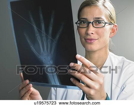 Smiling female doctor looking at x ray of hand. View Large Photo Image Stock Image - Smiling female doctor looking at x ray of hand.. Fotosearch