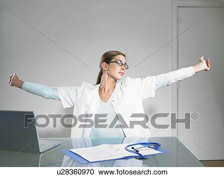 Stretching female doctor at her desk. View Large Photo Image Stock Image - Stretching female doctor at her desk.. Fotosearch
