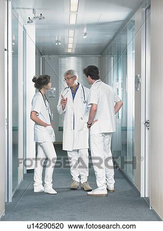 Three doctors in discussion in hospital lobby. View Large Photo Image Stock Image - Three doctors in discussion in hospital lobby.. Fotosearch