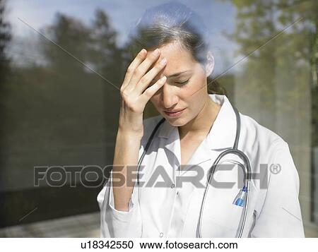 Stock Image - Young female doctor by the window. Fotosearch