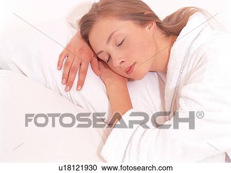Stock Image - bed, hand on cheek, indoors lying down, night dress. Fotosearch