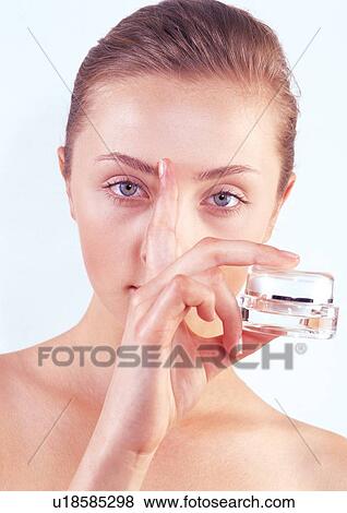 Stock Photo - young woman, human face, beauty, indoors, holding. Fotosearch