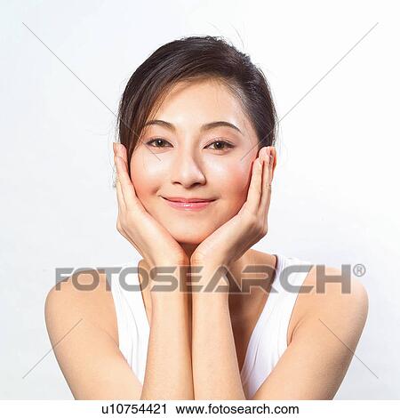 Stock Image - Smiling Asian woman holding her head. Fotosearch