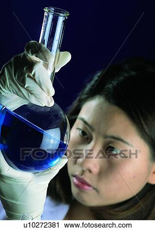 Stock Image - Close-Up, Beaker, Blue, Black Hair, Black Background, Asian Ethnicity. Fotosearch