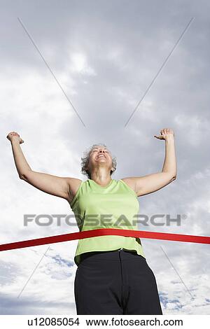 Picture - Female runner crossing finishing line (low angle view). Fotosearch