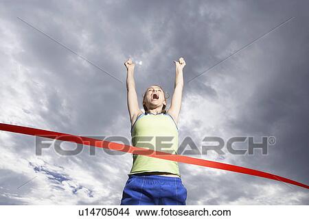 Female runner crossing finishing line (low angle view) View Large Photo Image Picture - Female runner crossing finishing line (low angle view). Fotosearch