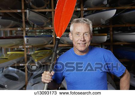 Mature man holding oar by kayaks View Large Photo Image Stock Image - Mature man holding oar by kayaks. Fotosearch