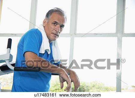 Stock Image - Mature man on exercise machine (portrait). Fotosearch