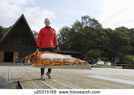 Stock Photo - Senior man carrying a kayak. Fotosearch